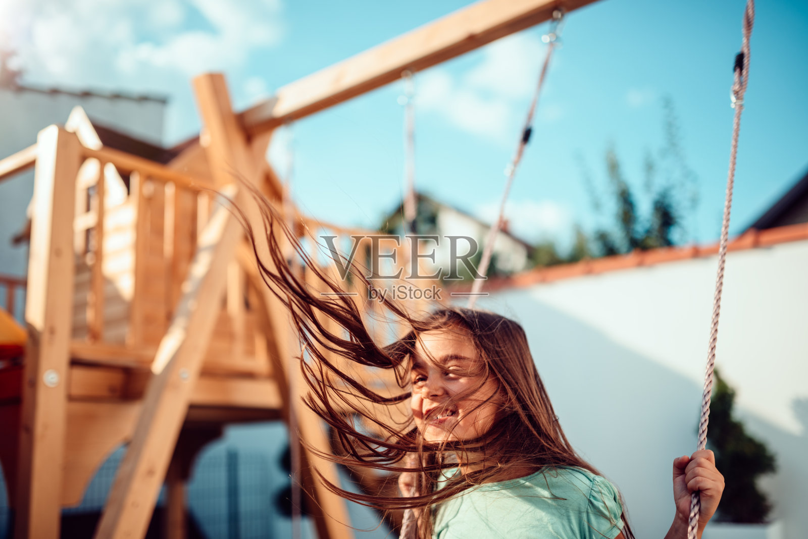 一个快乐的小女孩坐在秋千上，长发飞扬照片摄影图片