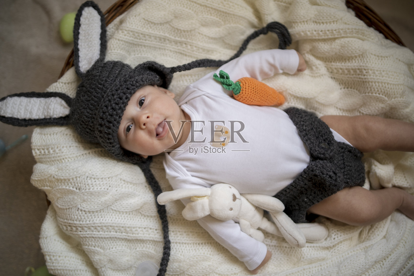 婴儿与兔子耳朵服装复活节躺在白色床上亚麻床单鹌鹑蛋。复活节儿童服装。照片摄影图片