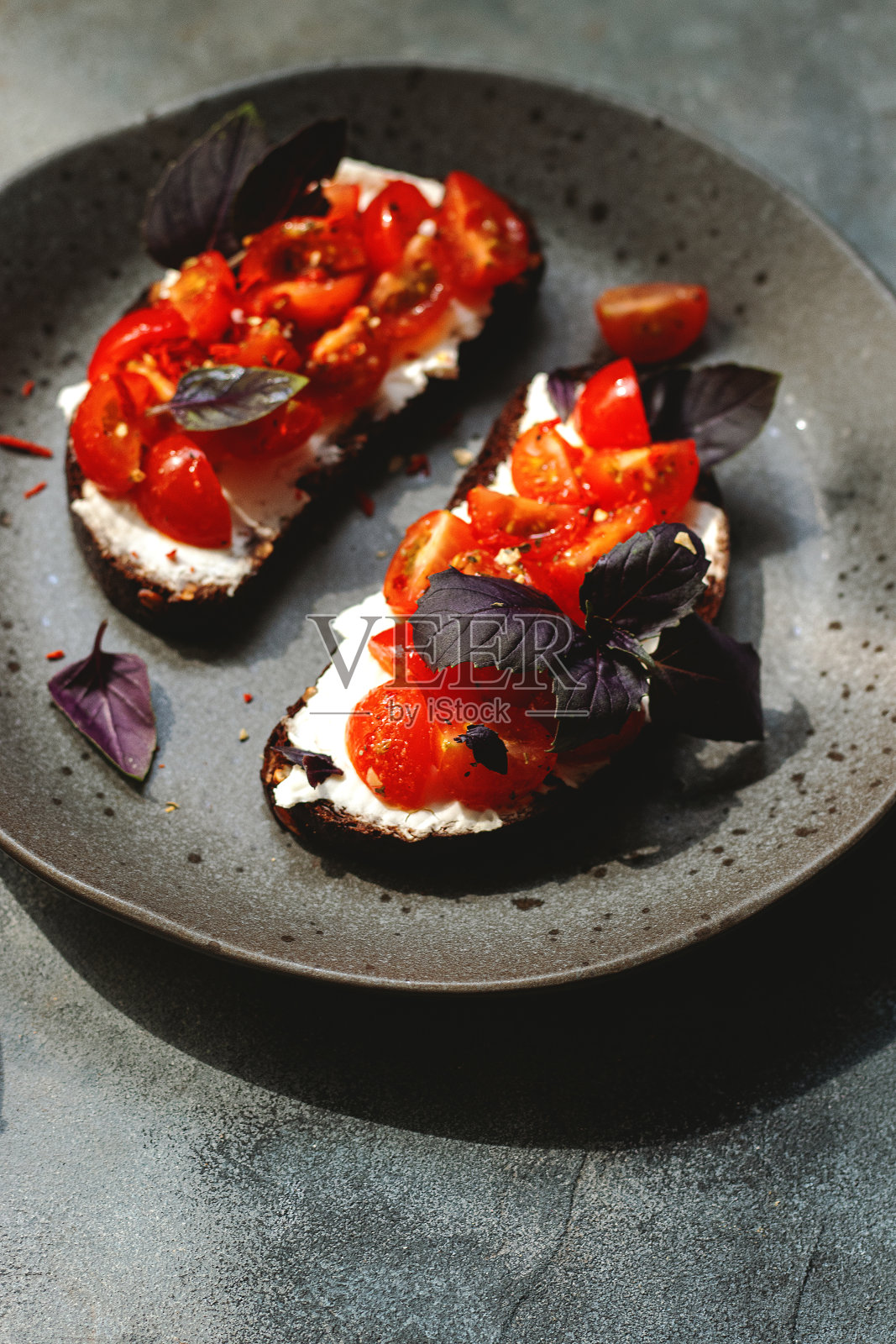 意式烤面包，配以樱桃番茄，白干酪，罗勒，香草，大蒜，灰色背景。自然强光照片摄影图片