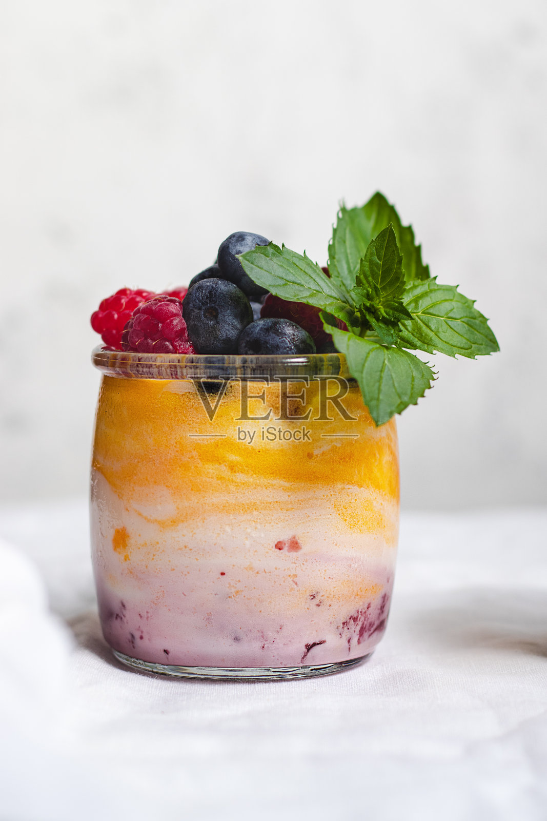 酸奶，芒果和浆果果酱，蓝莓，覆盆子和薄荷叶在杯子里照片摄影图片