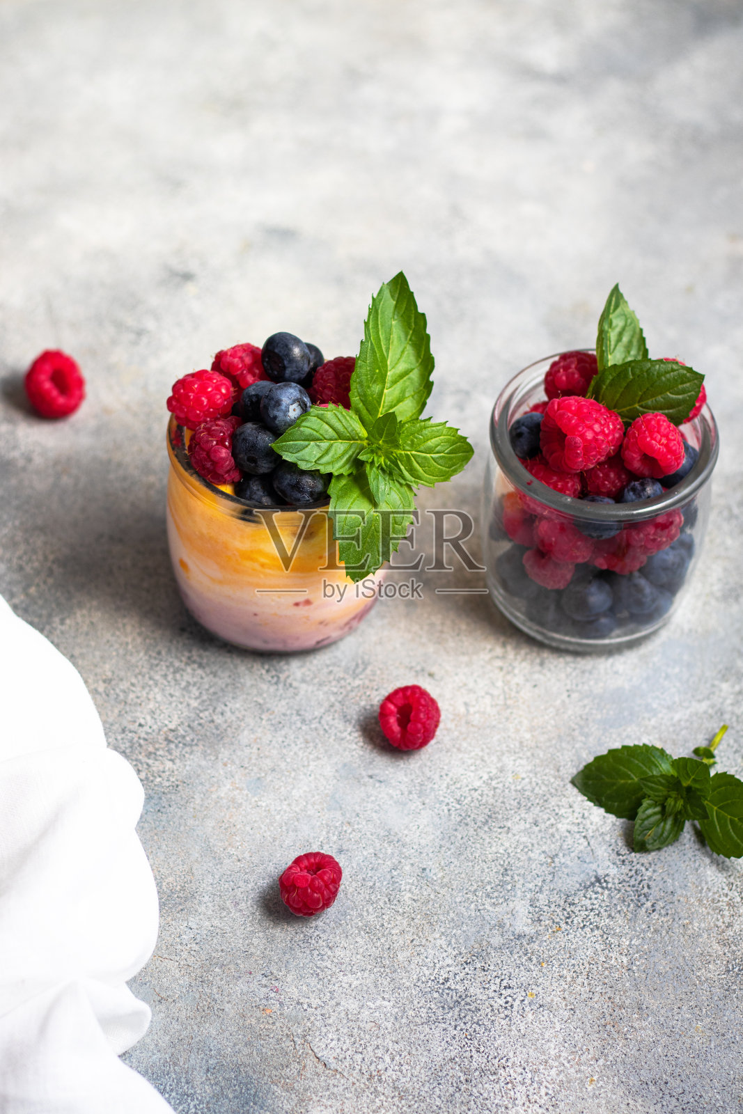 酸奶，芒果和浆果果酱，蓝莓，覆盆子和薄荷叶在杯子里照片摄影图片