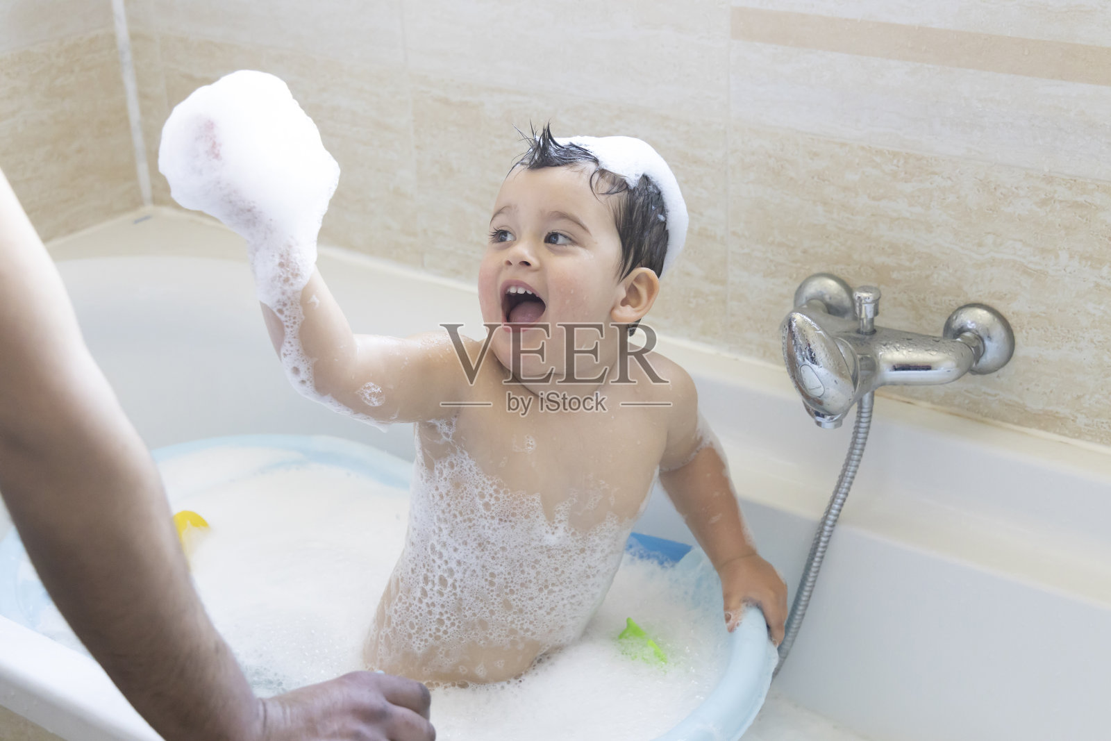 一个可爱的小男孩正在浴室里洗澡。肥皂水。照片摄影图片