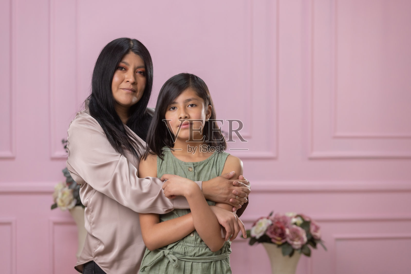 墨西哥母亲和女儿拥抱在粉红色背景孤立照片摄影图片