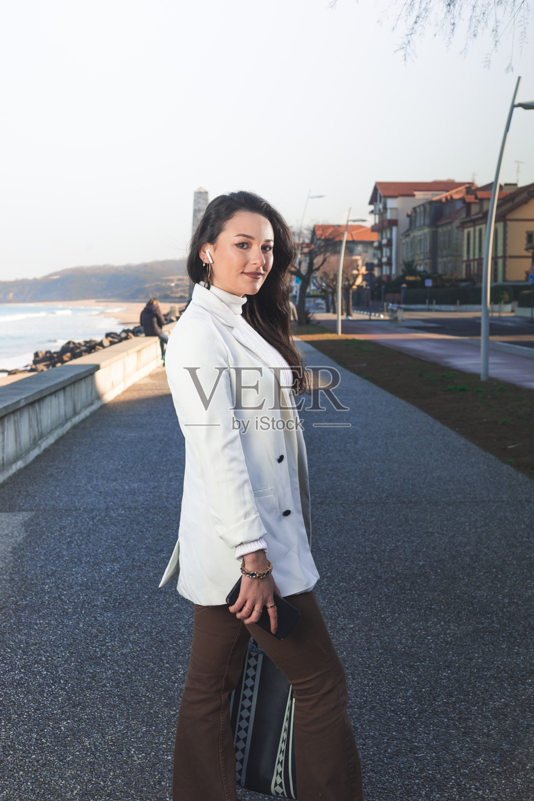 年轻的白人妇女在海滨散步。照片摄影图片