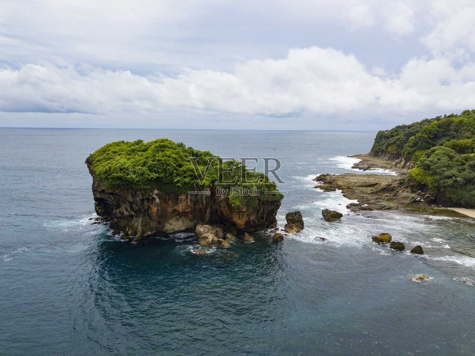 海滩上树木丛生的珊瑚岛，被海浪袭击照片摄影图片