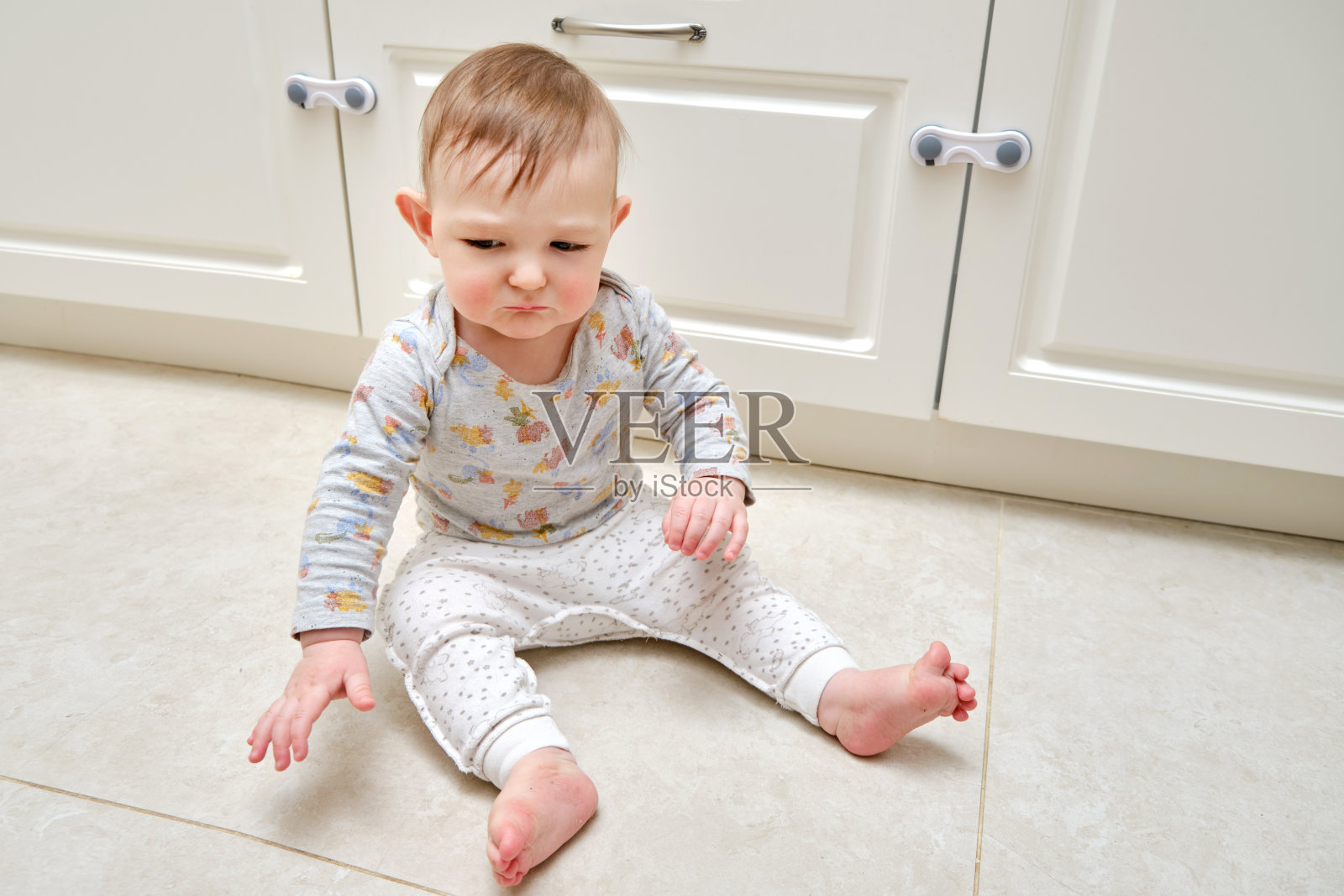 蹒跚学步的婴儿在上锁的抽屉柜附近打架。可怜的孩子和壁橱橱柜门，小孩照片摄影图片