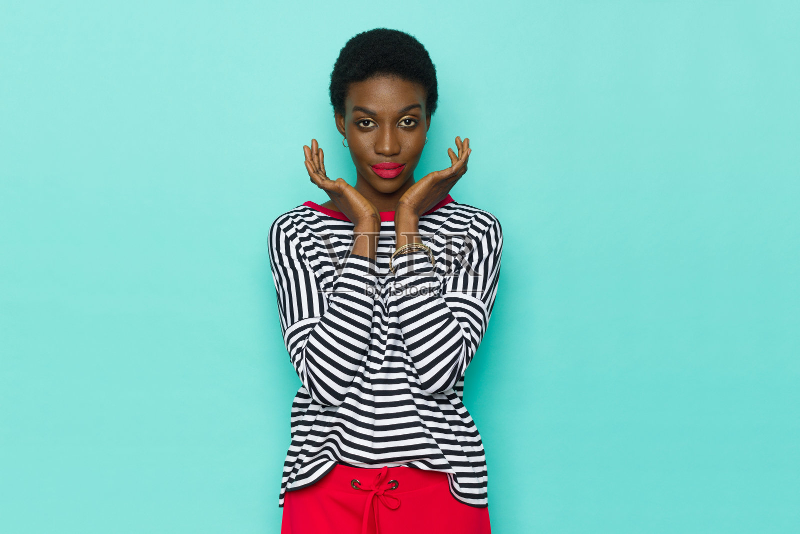 美丽的黑人妇女在条纹衬衫是摆姿势的头在手中。照片摄影图片