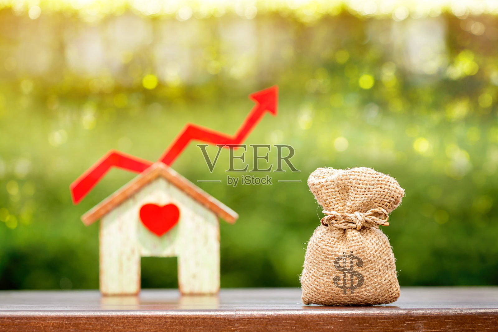 钱袋和家以心和红色箭头图形的增值放在桌子上的公共公园的散景背景，为金融业务投资和基金房地产的概念。照片摄影图片