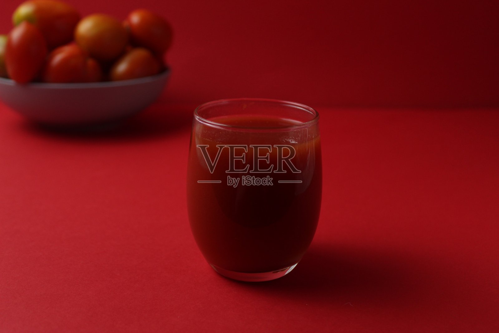 红色番茄汁在一个杯子旁边的番茄躺在一个盘子上的红色背景与文字的地方。健康食品饮料维生素照片摄影图片