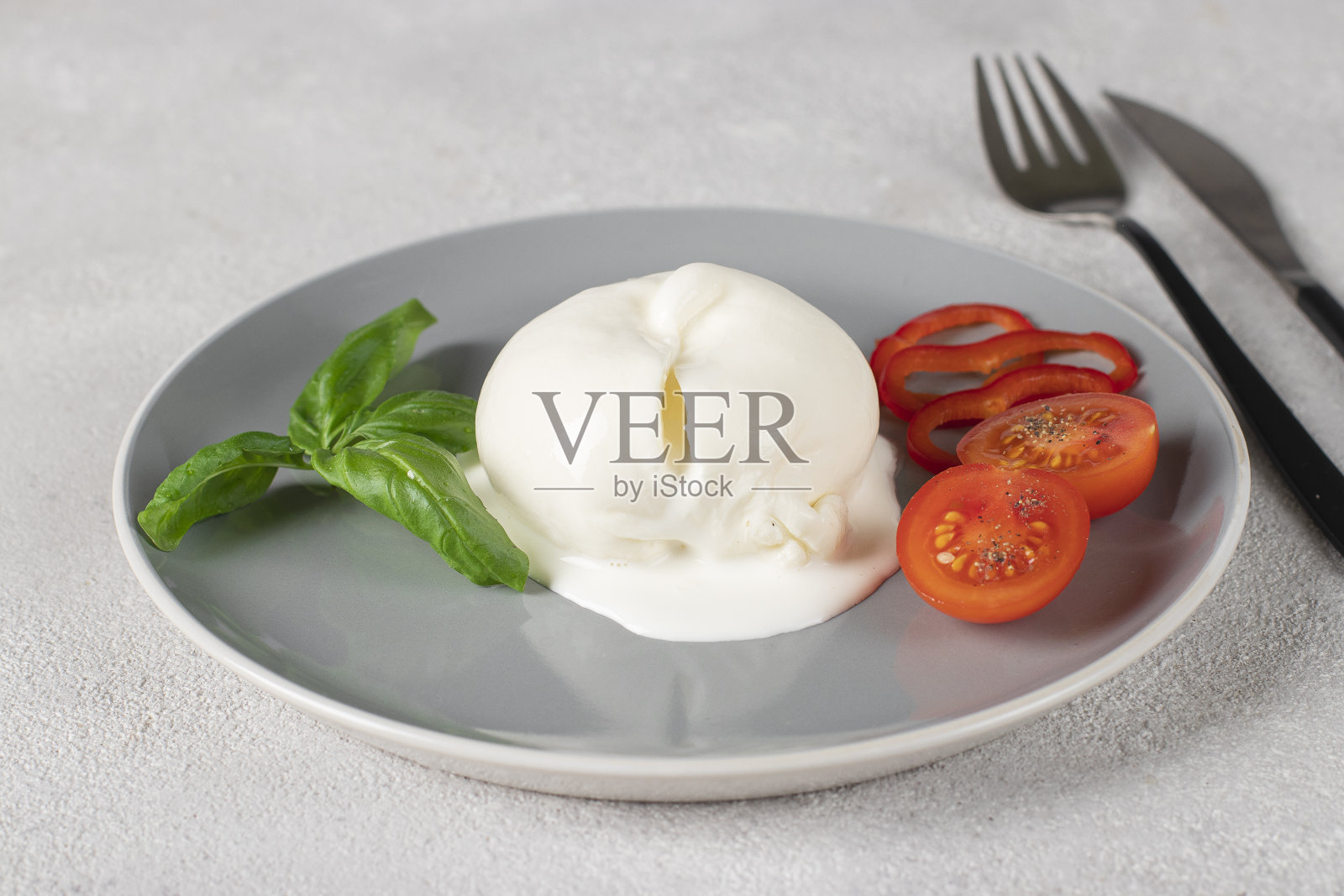 灰色盘子上的意大利布拉塔奶酪，配上罗勒和樱桃番茄。意大利国旗的颜色照片摄影图片