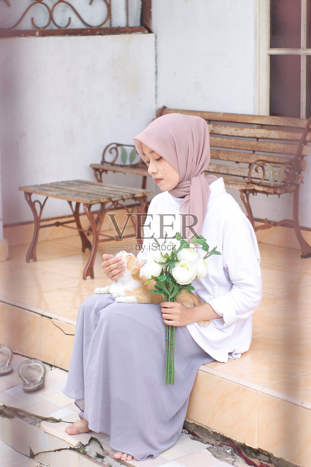 年轻的女人在房子前面和一只宠物猫玩耍照片摄影图片