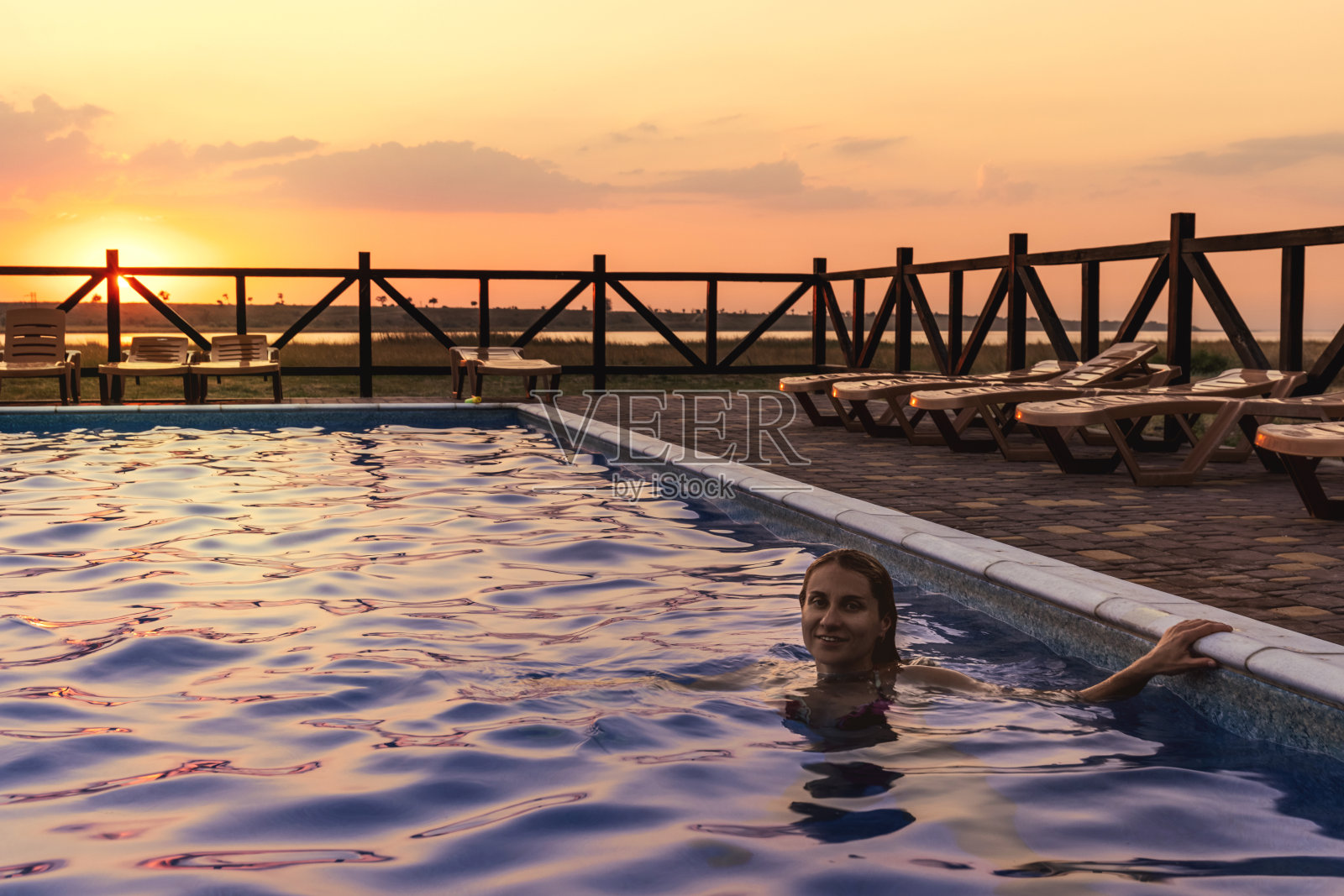 一个女人游泳在一个清澈的水的背景是一个夏天的夕阳度假照片摄影图片