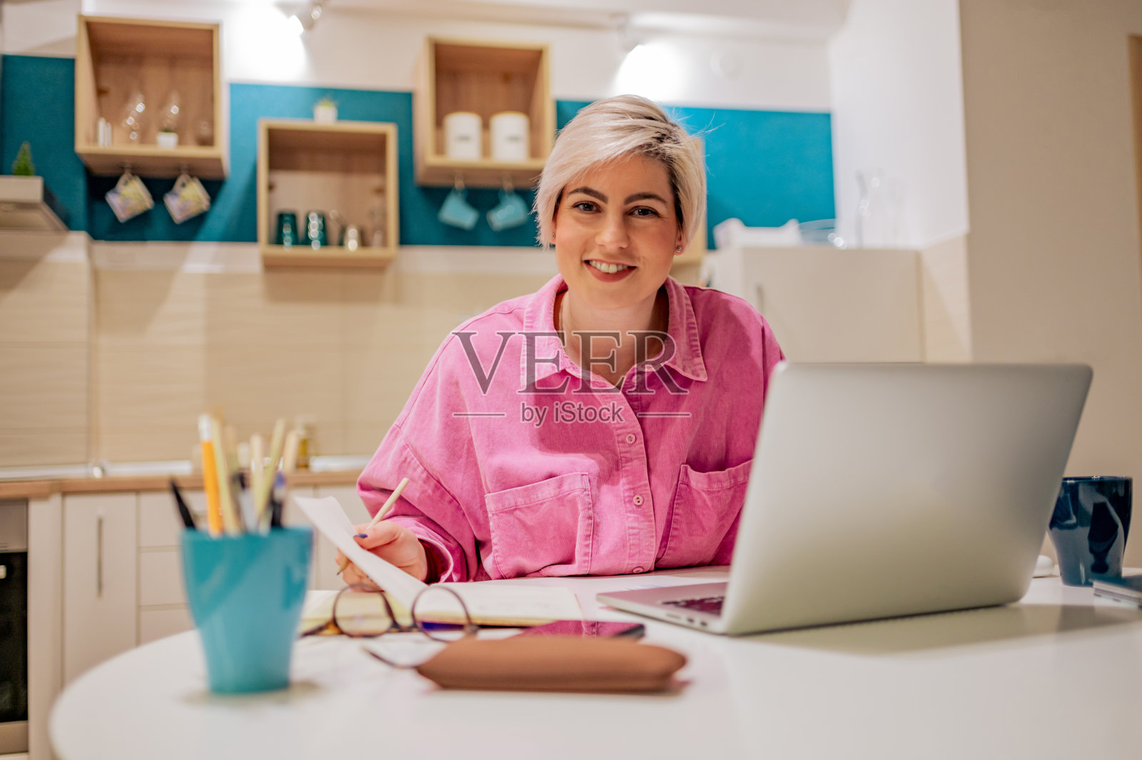 留短发的女人在家用笔记本电脑工作，写笔记照片摄影图片