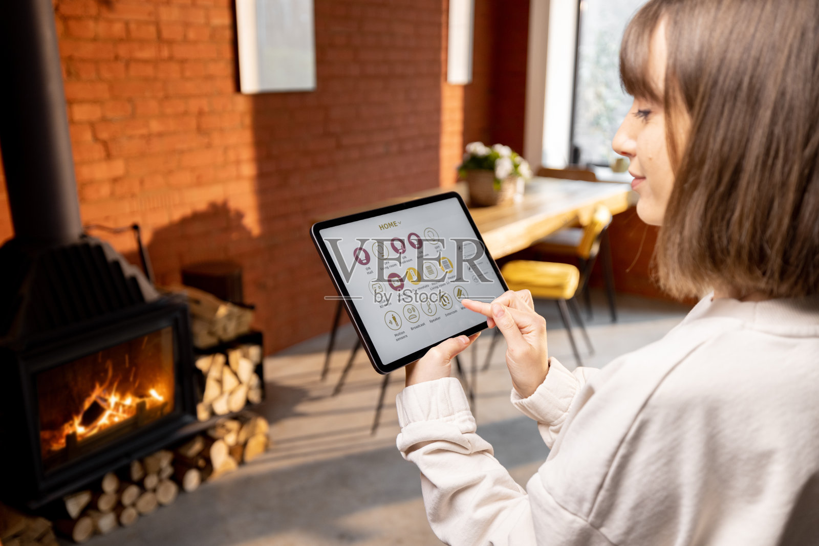女性通过在家使用数字平板电脑上的智能家庭应用程序远程控制家庭设备照片摄影图片