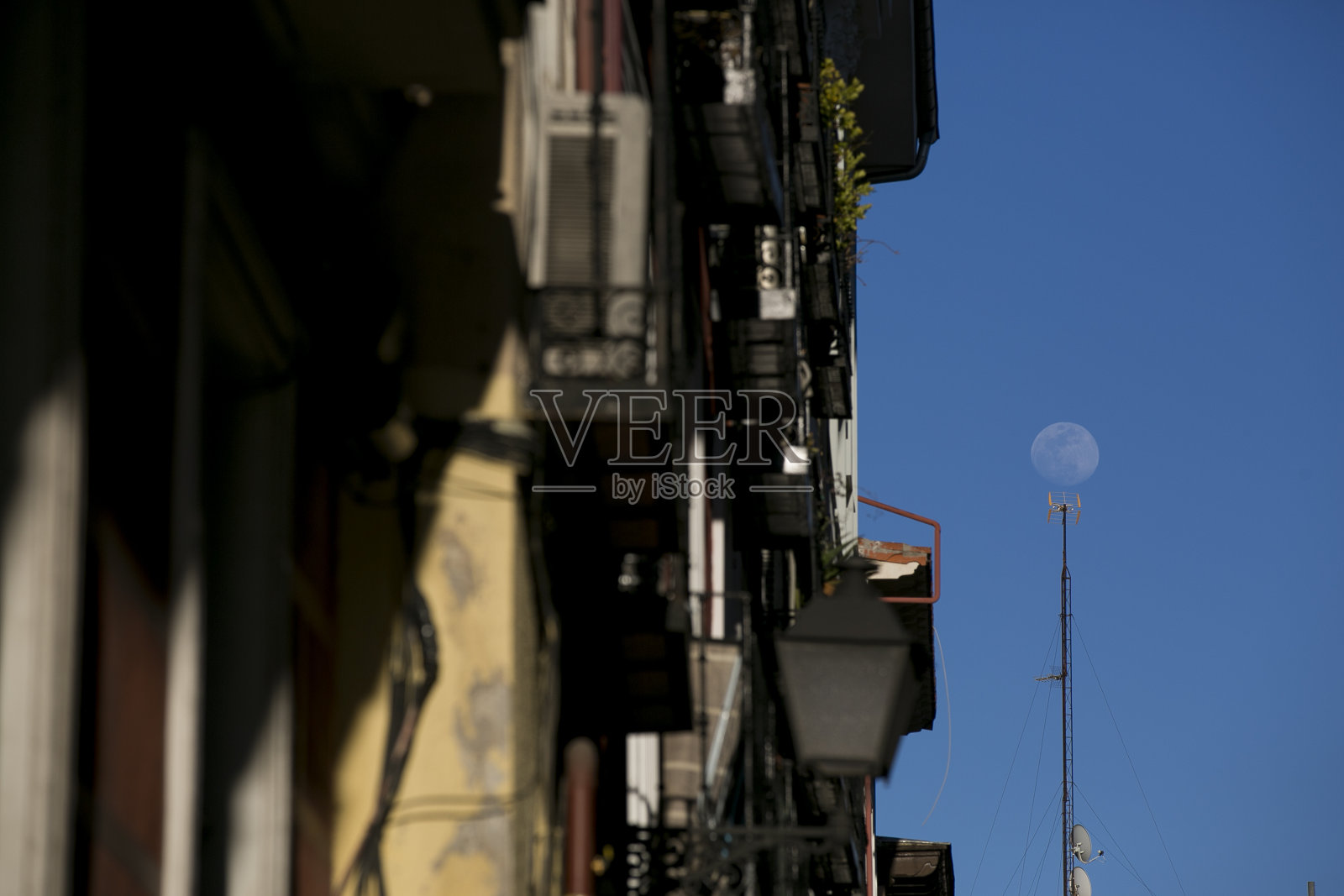 以阳台和月亮为背景的建筑。西班牙马德里的街道。照片摄影图片
