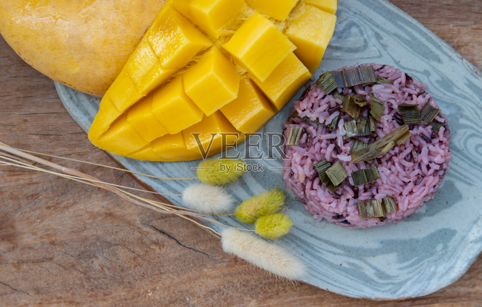 新鲜成熟的黄色芒果(梭鱼芒果)和大米浆果的特写，盖上香兰叶。照片摄影图片