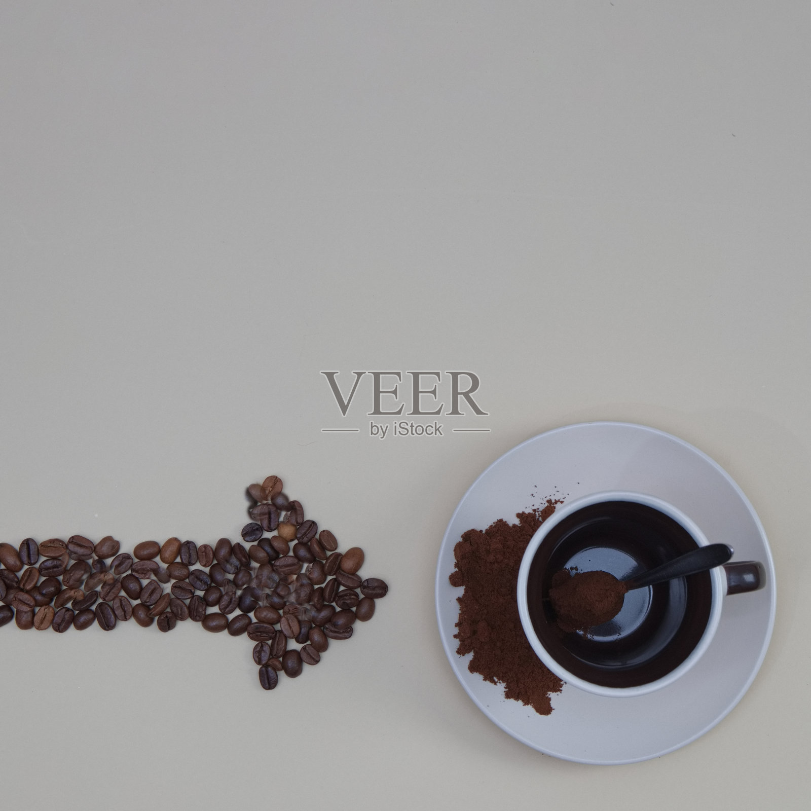 咖啡杯，勺子和咖啡豆箭头复制空间在米色背景。最小的平面场景。照片摄影图片