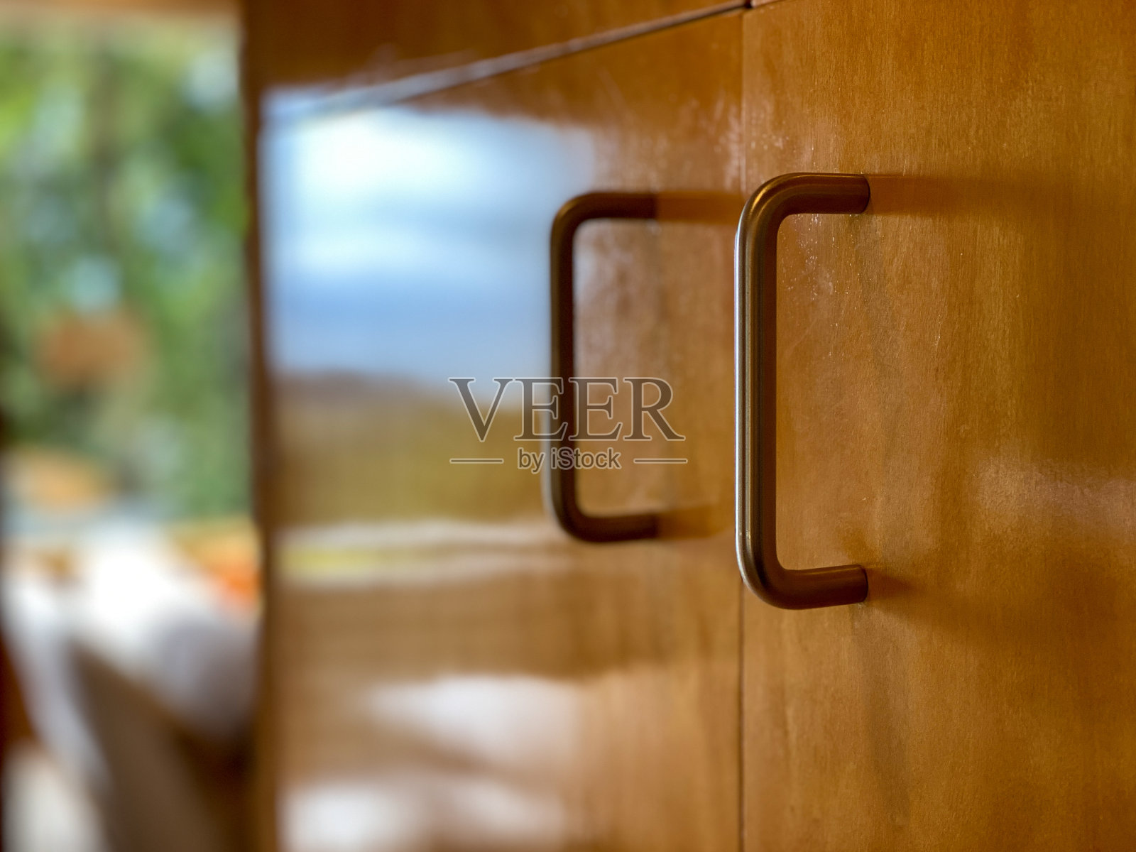 厨房木制橱柜上的金属弧形把手。照片摄影图片