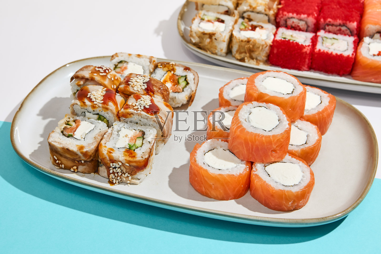 寿司集:费城，加利福尼亚，加拿大maki卷在陶瓷板。时尚的寿司在最小的风格。现代日本的菜单概念。寿司组合在彩色的背景。照片摄影图片