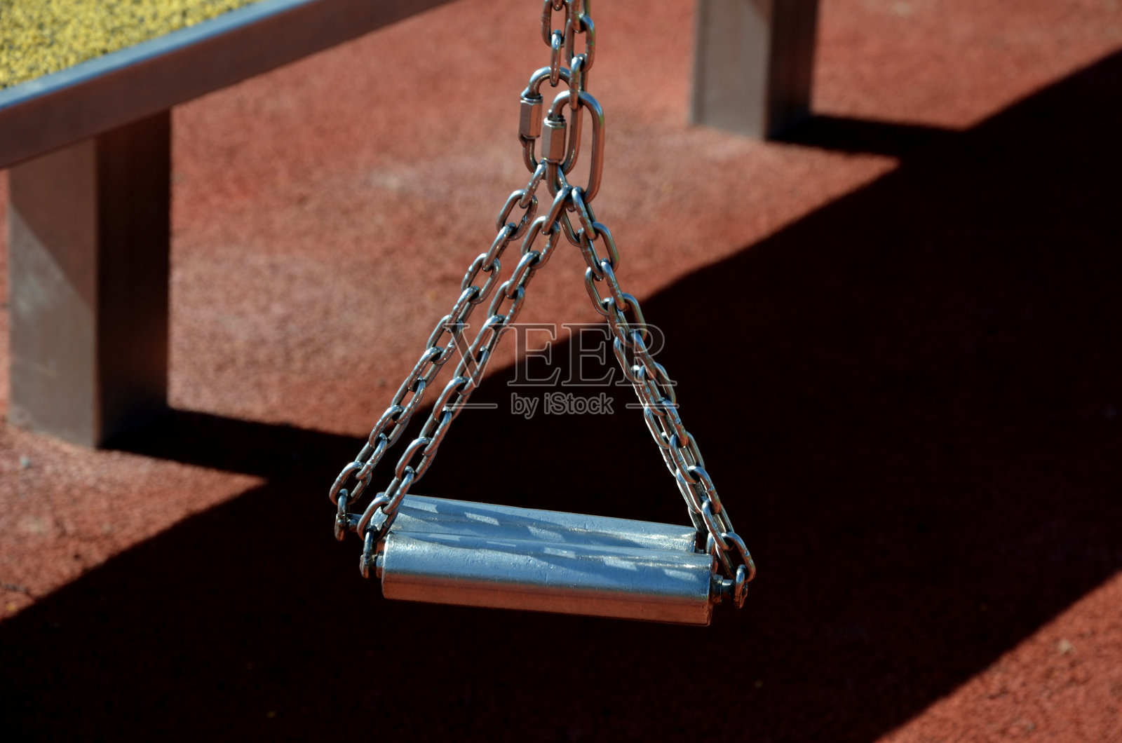 在健身运动场上，不锈钢工具就像有链条和把手的刑具。柔软的橡胶表面运动地面户外健身房。男子持有滑轮，加强肌肉照片摄影图片