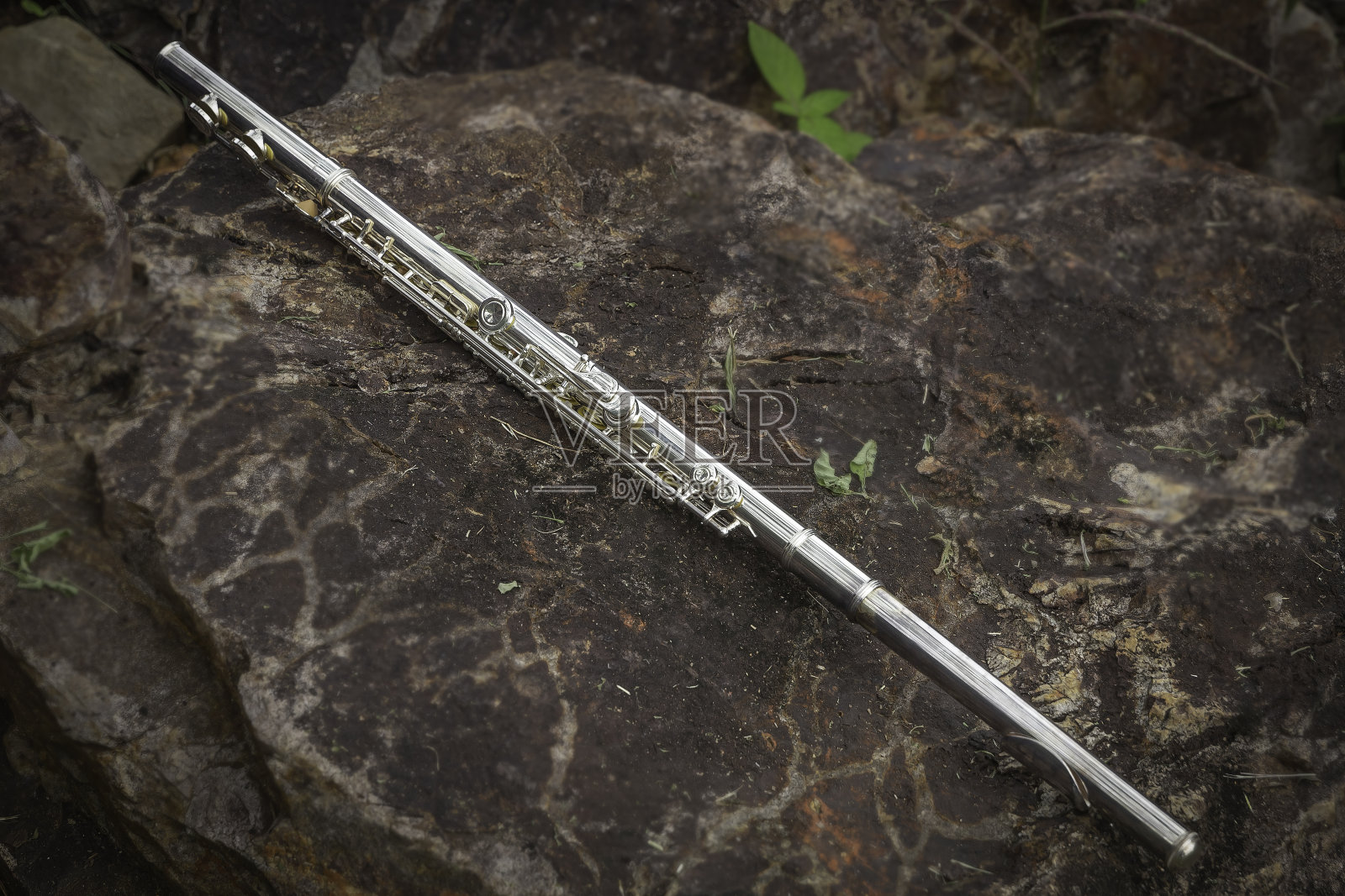 把笛子放在石头上，在练习休息时间为音乐会做准备。照片摄影图片