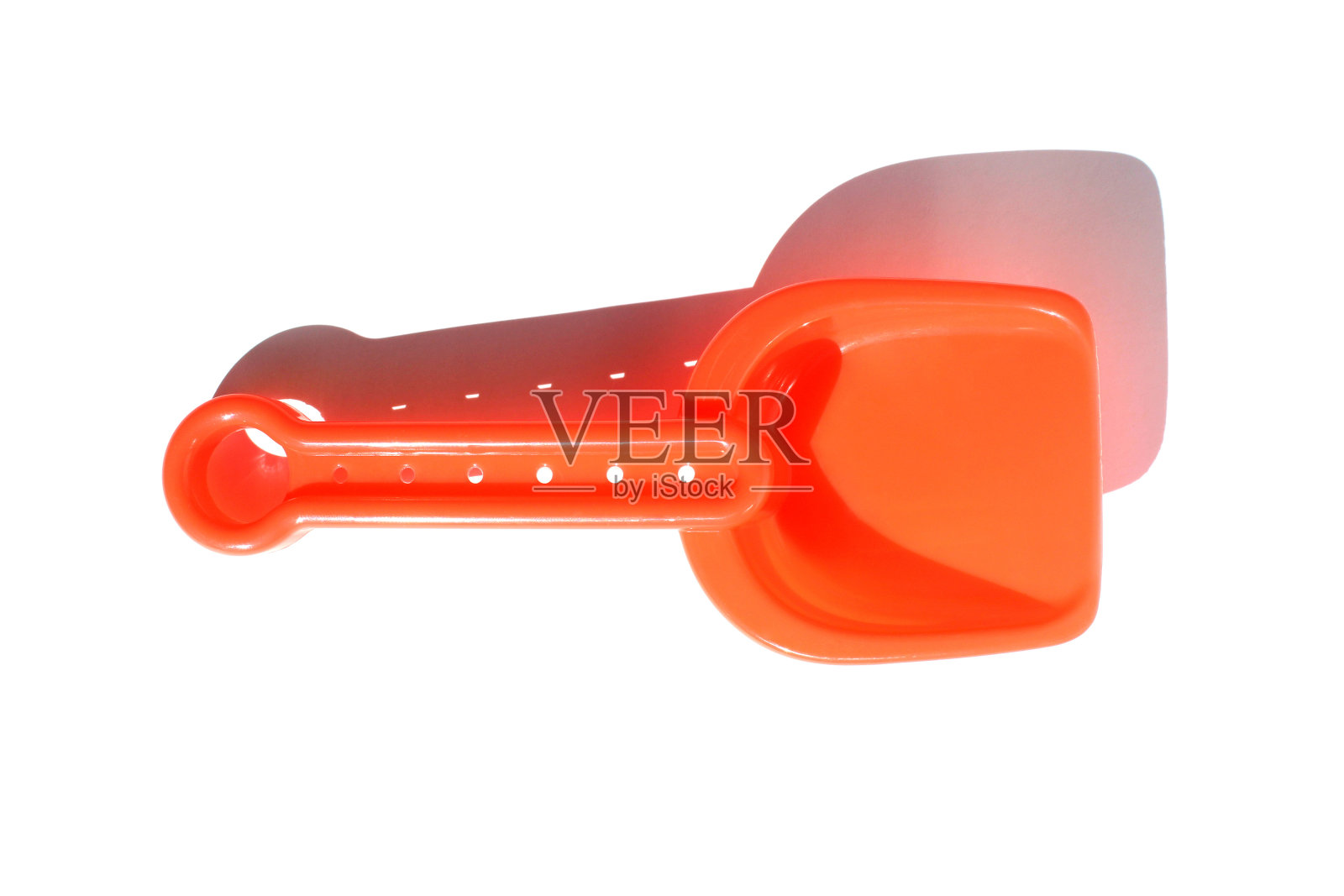 白色背景上放着一把红色玩具铲子。照片摄影图片