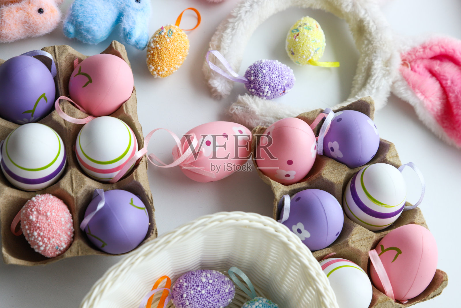 彩色复活节装饰品和鸡蛋在托盘，兔子，一个篮子与鸡蛋在白色背景，特写。节日的概念照片摄影图片