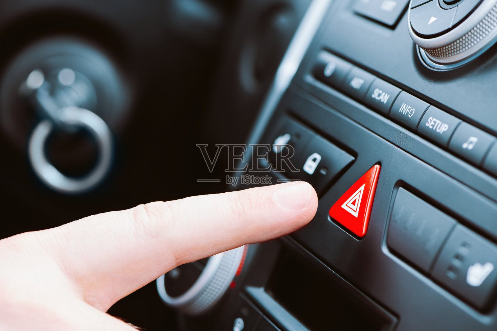 一名男子按下了汽车仪表盘上的三角形紧急按钮。近景与浅景深。照片摄影图片