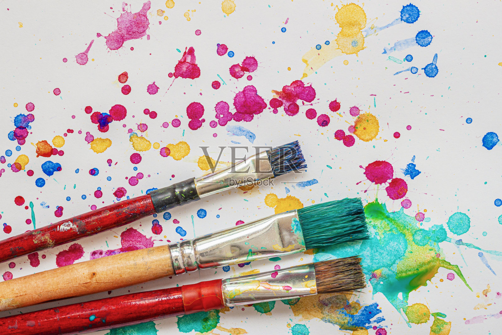 艺术家用画笔在彩色水彩的背景上喷溅，生动的斑点照片摄影图片