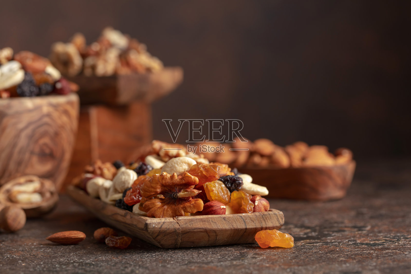 混合坚果和葡萄干在棕色乡村背景。照片摄影图片