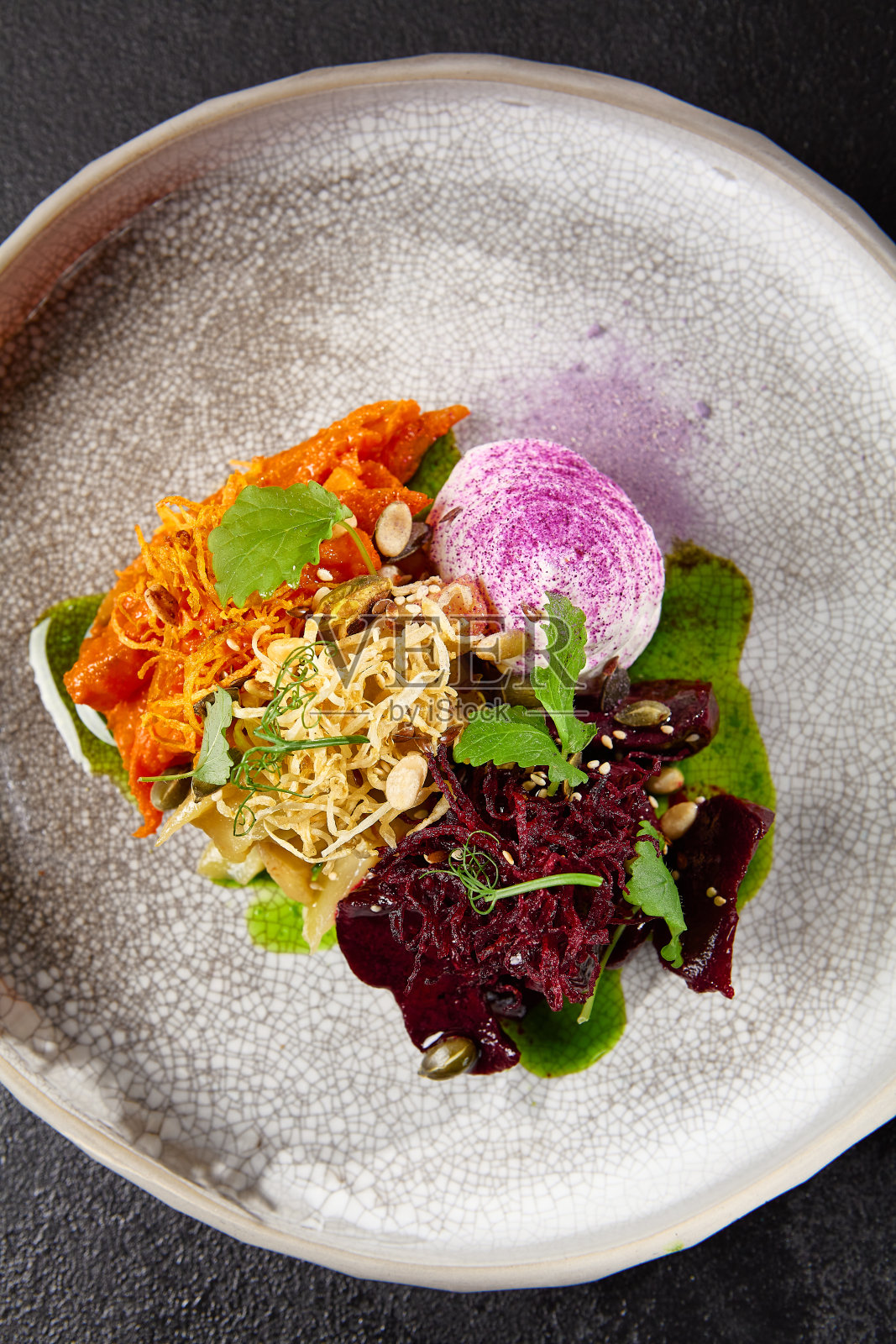 手工陶瓷餐具中的烤根茎蔬菜。素食——现代陶器上的焦糖胡萝卜、甜菜根和芹菜。素食创新食谱照片摄影图片