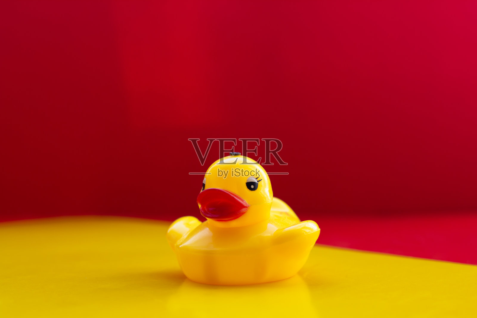 黄色橡胶鸭与大红唇在黄红色的背景与文字的空间。黄色的玩具鸭子。人工大嘴唇。肉毒杆菌的嘴唇。鸭嘴。本空间照片摄影图片