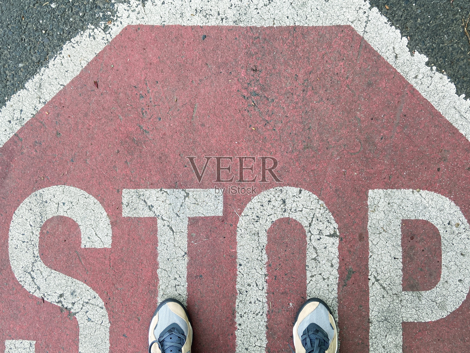 两只脚踩在柏油路上的停车标志上照片摄影图片