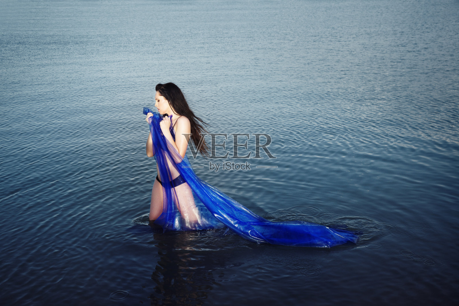 系着蓝色围巾站在水中的性感女人照片摄影图片