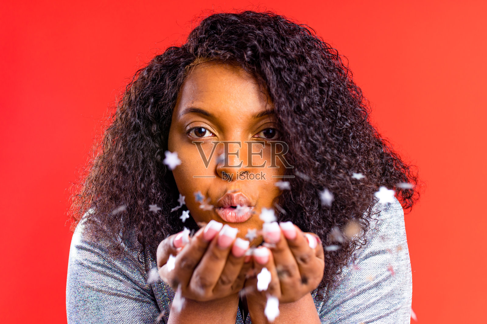 非洲裔美国妇女吹下闪亮的星星从棕榈树在红色工作室新年或圣诞节梦想照片摄影图片