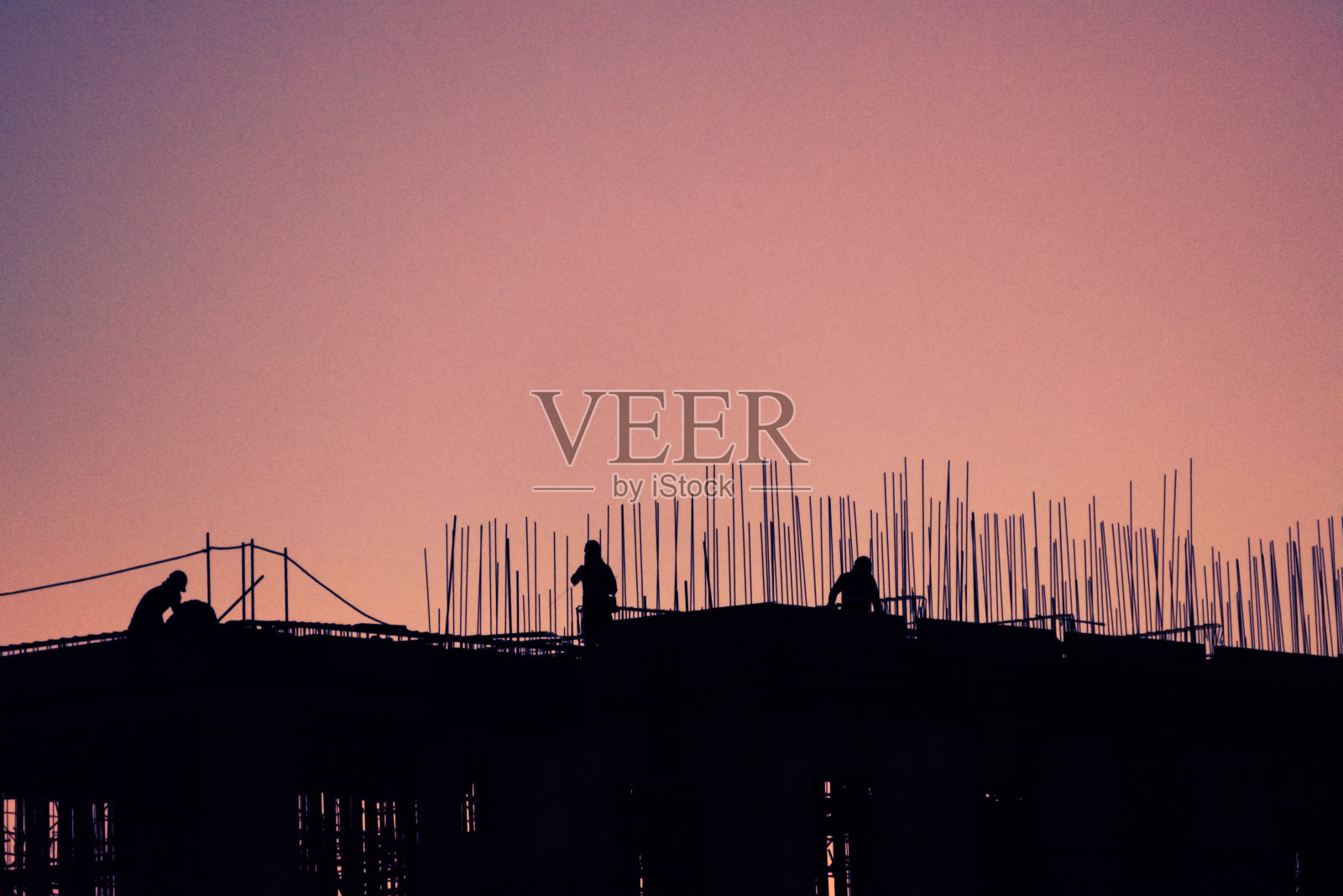 正在建设中的建筑阳台上工作的男人的剪影，拉丁美洲戏剧性的日落。照片摄影图片