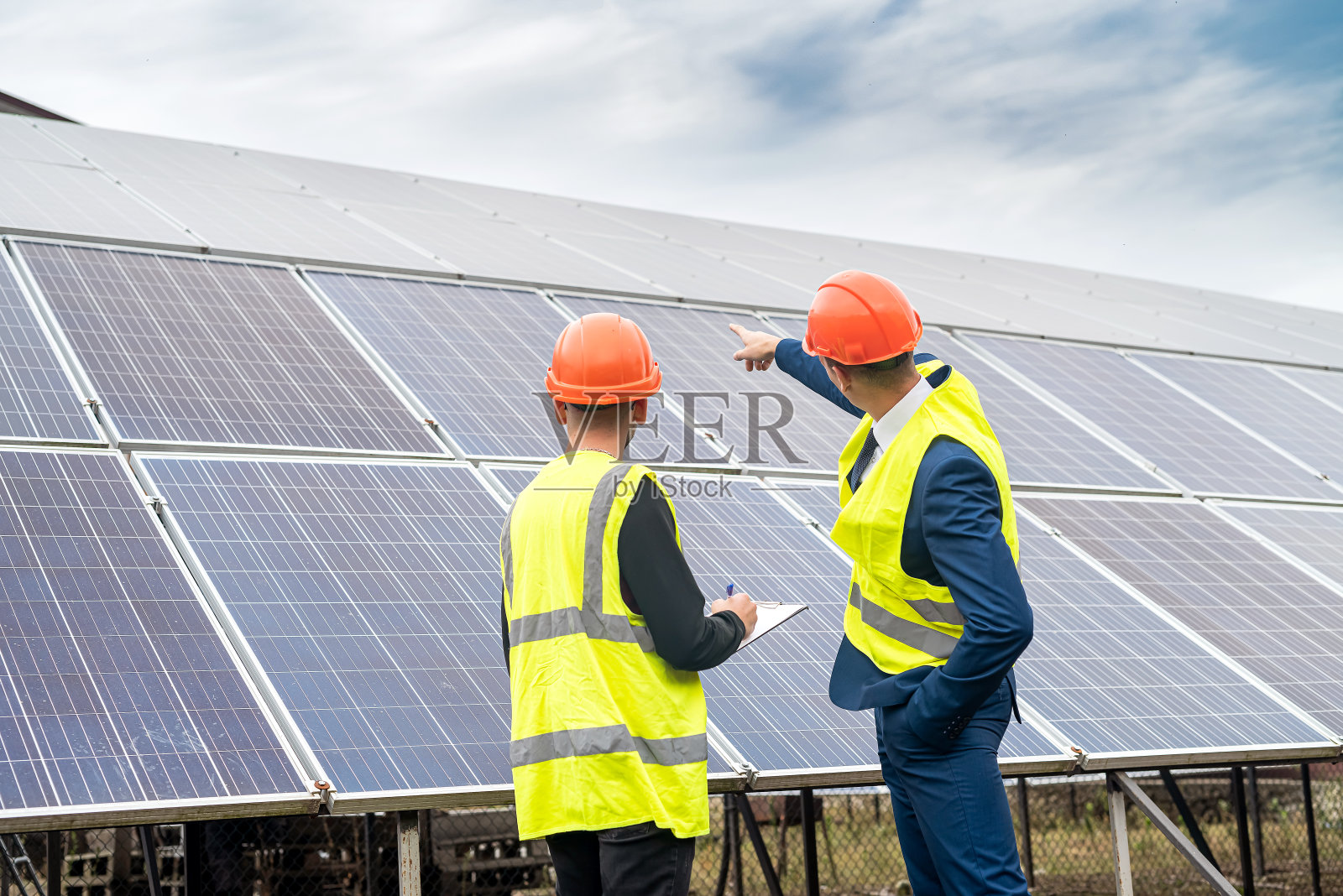 身穿制服、头戴头盔的商人告诉工人安装太阳能电池板的计划。照片摄影图片