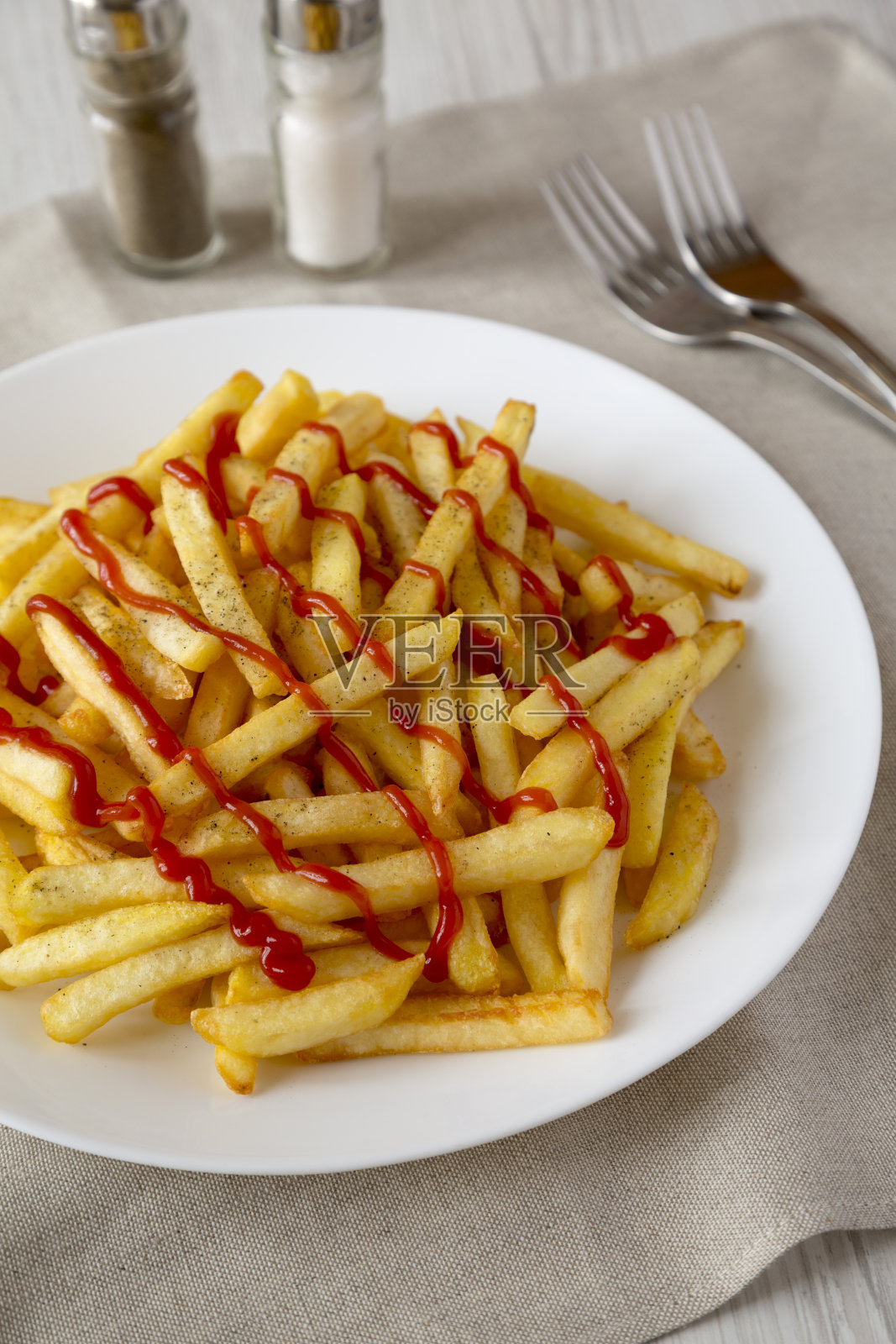 自制薯条，番茄酱，盐和胡椒在白色盘子上的白色木制背景，侧视图。特写镜头。照片摄影图片