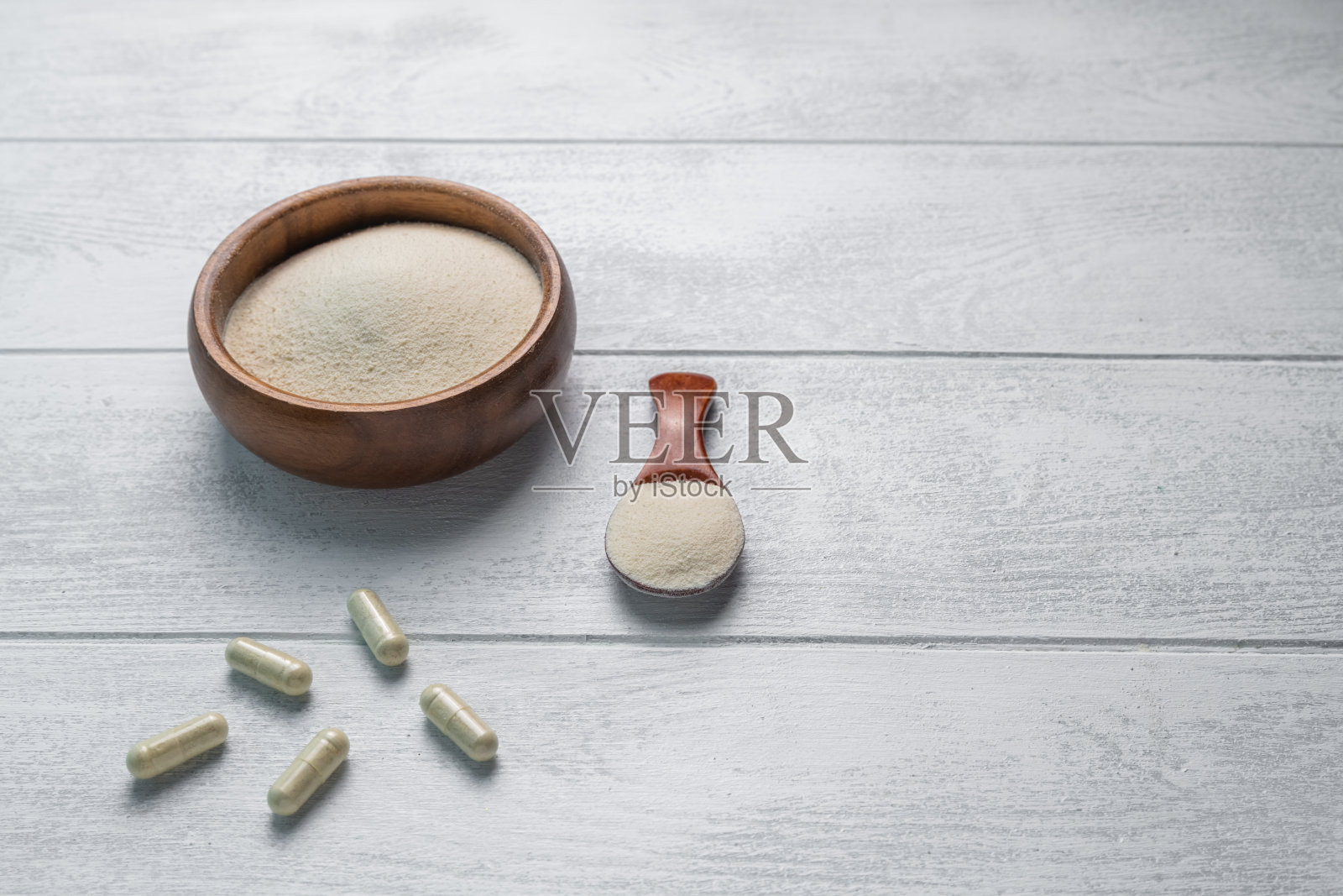 胶原蛋白粉在木制白色背景的碗和勺子。照片摄影图片
