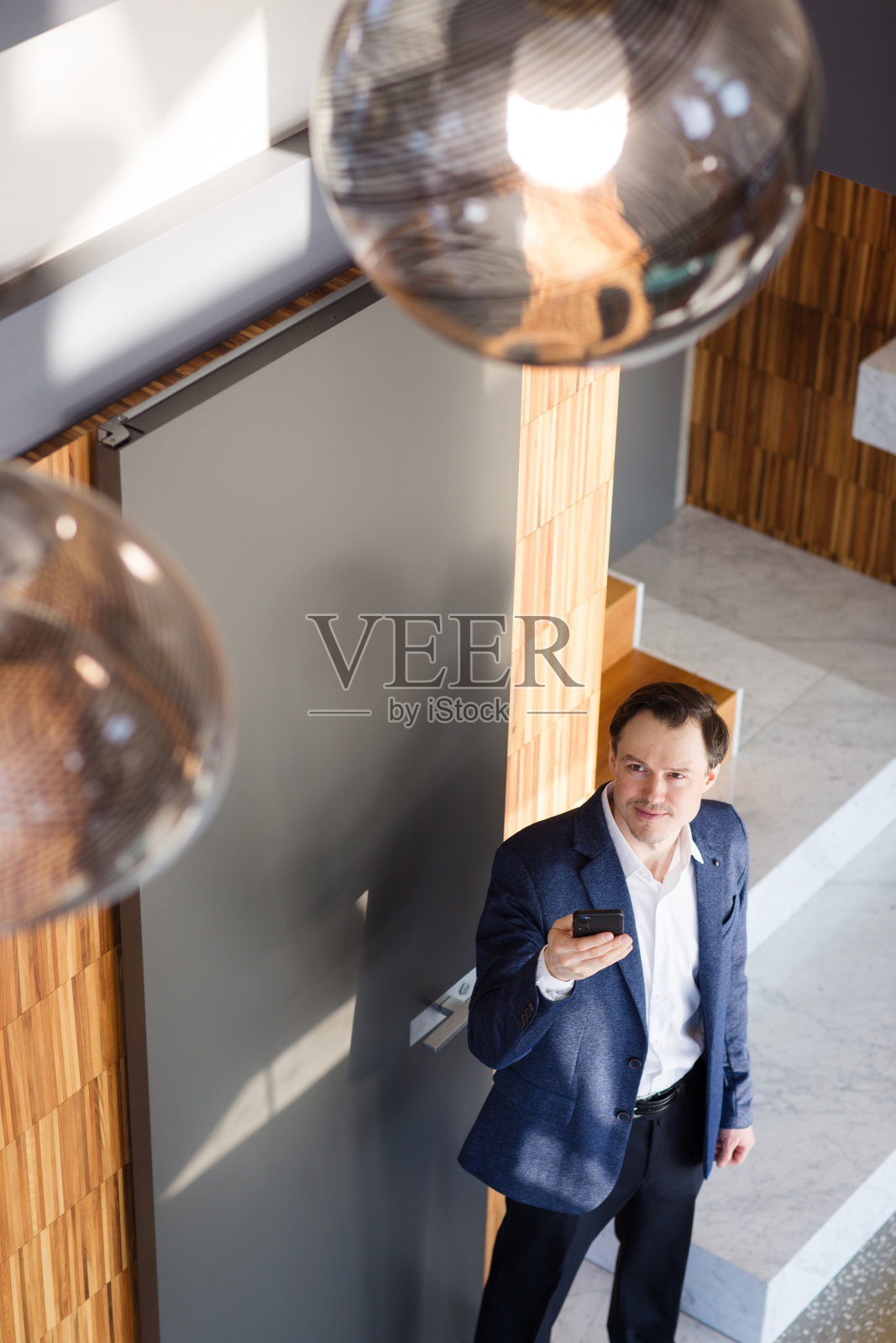 一名男子在家里用数字平板电脑控制家里的灯光。概念智能家居和灯光控制与手机，移动设备。照片摄影图片