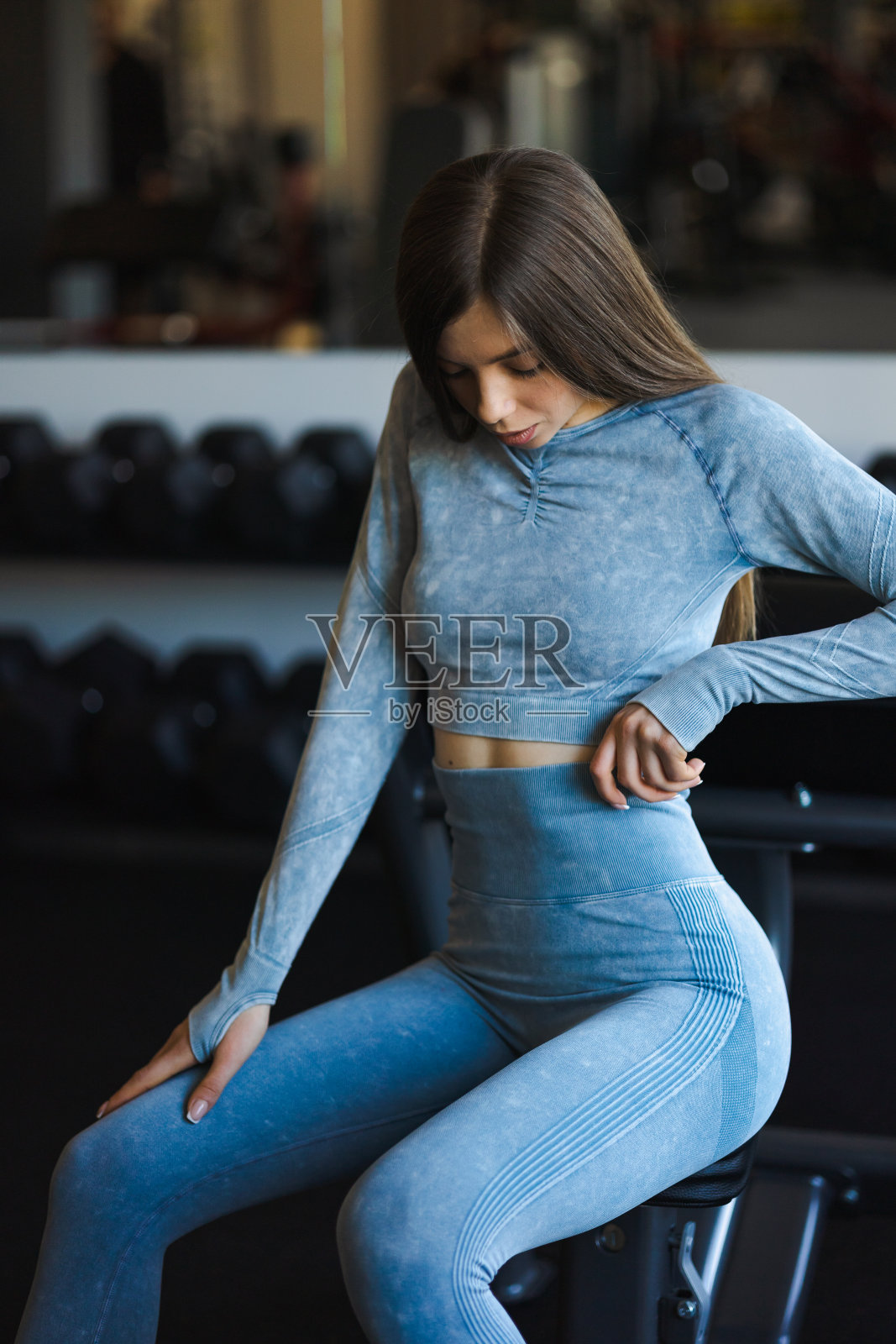 穿着蓝色健身服的漂亮年轻女子在健身房摆姿势照片摄影图片