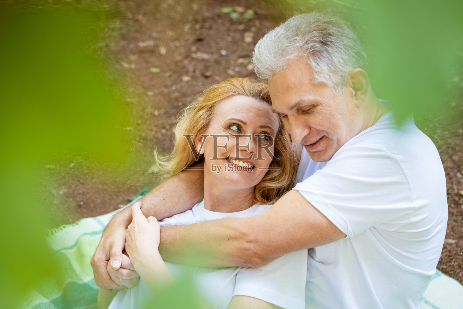 公园里，一对成年夫妇在毯子上拥抱照片摄影图片