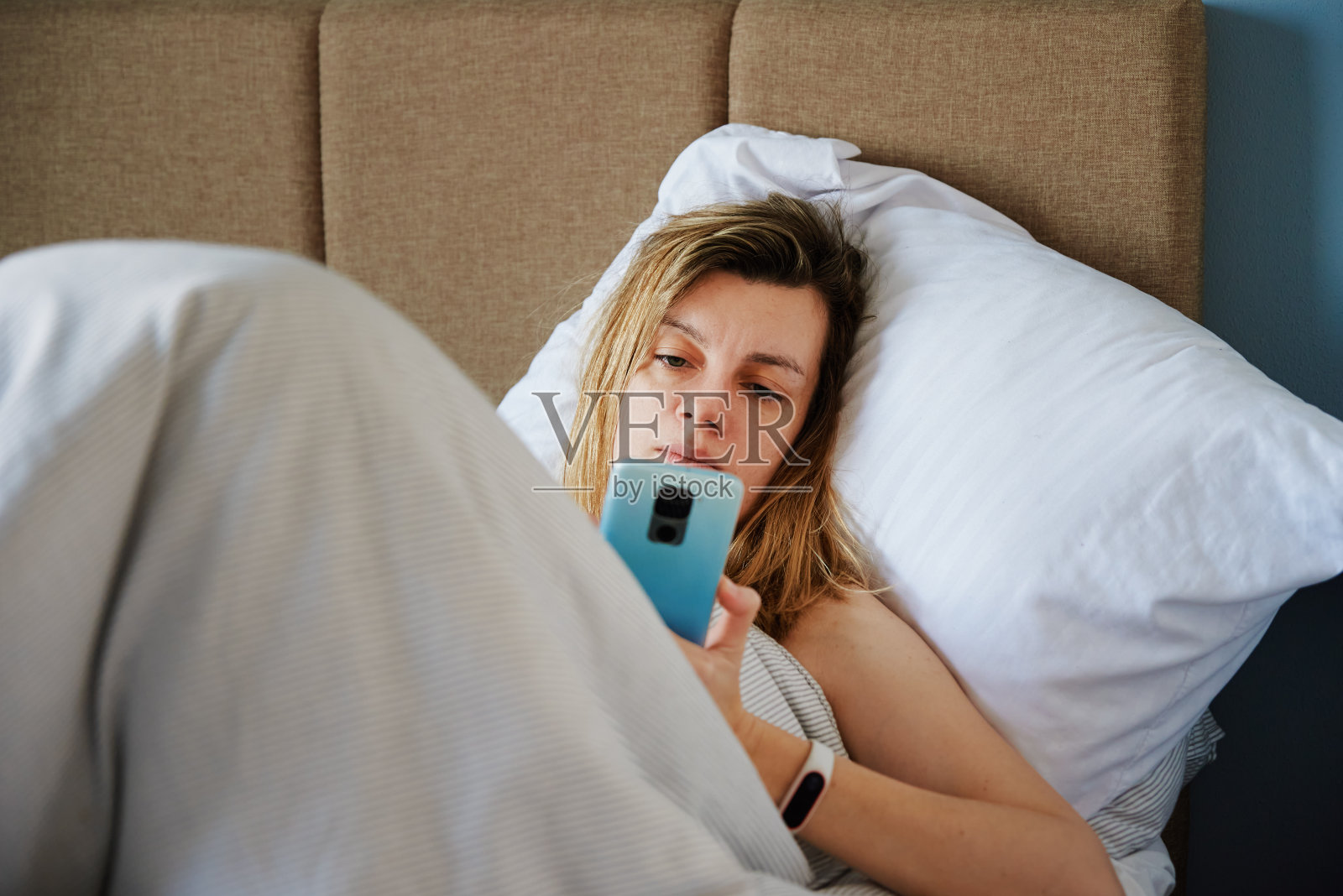 女人在床上使用智能手机，社交媒体，慵懒的周末照片摄影图片