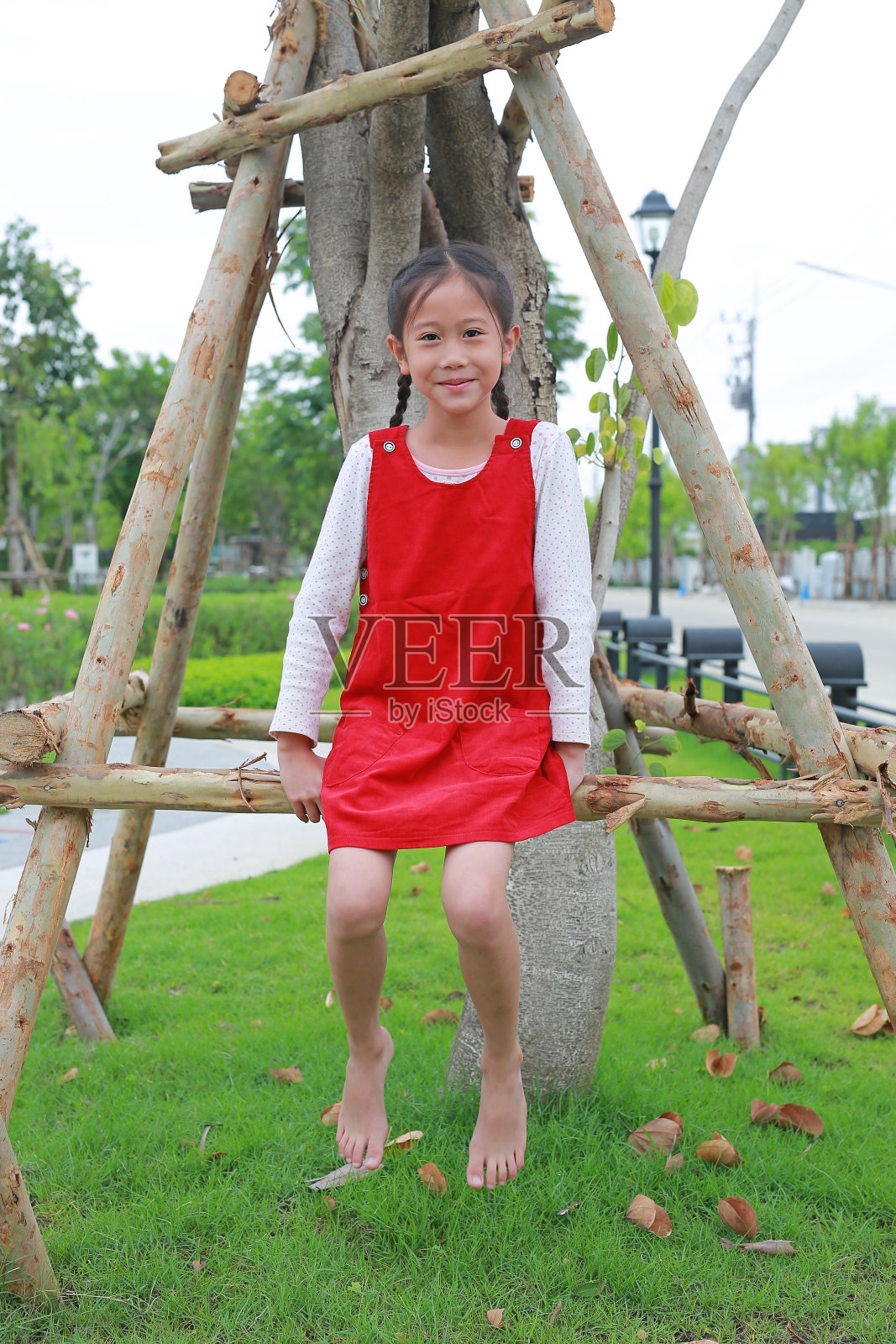 可爱的亚洲女孩坐在自然花园的一棵树上。照片摄影图片