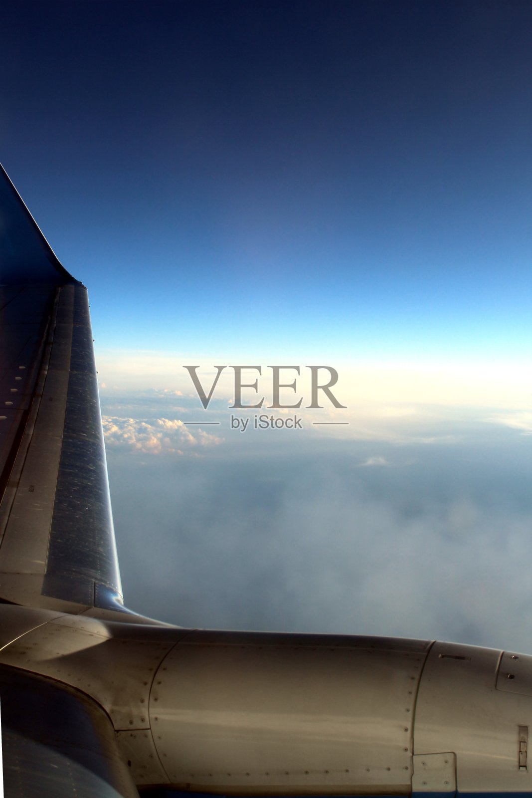 飞机在云层上方飞行。飞机的机翼看得见。照片摄影图片