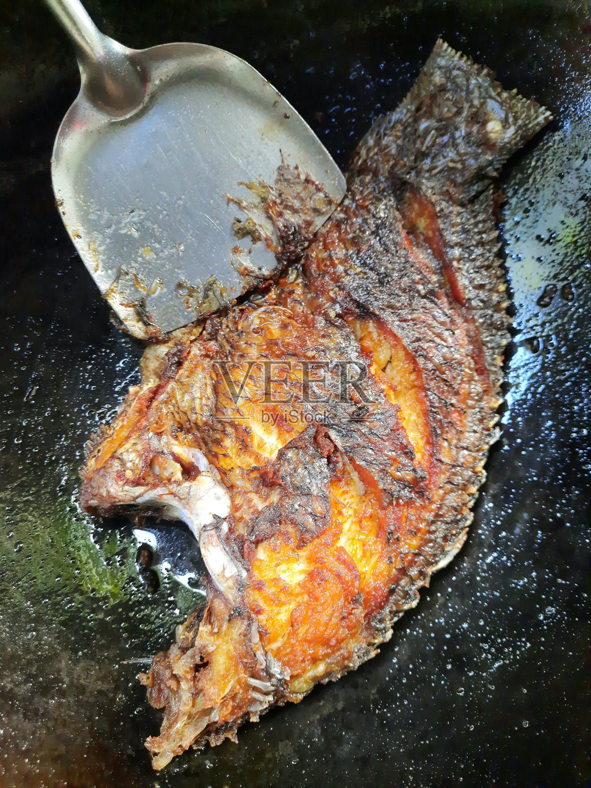 粘勺和油炸罗非鱼-食品的准备。照片摄影图片