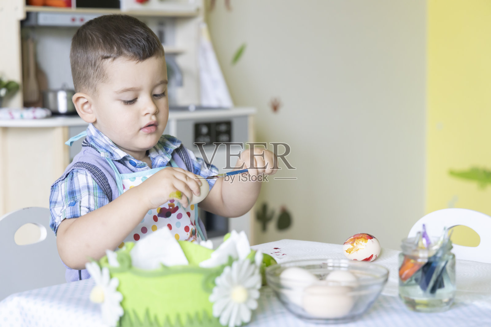 一个可爱的小男孩为复活节画彩蛋。复活节快乐。照片摄影图片