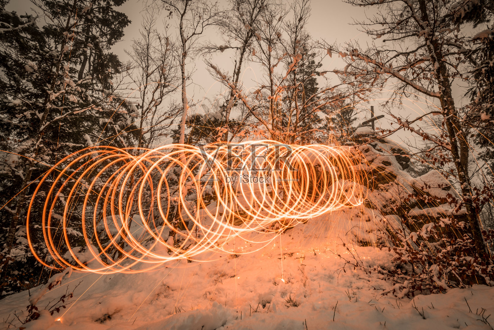 夜晚，金色的火花喷在雪山上，火花由发光的钢丝绒抛成一个圈，德国照片摄影图片