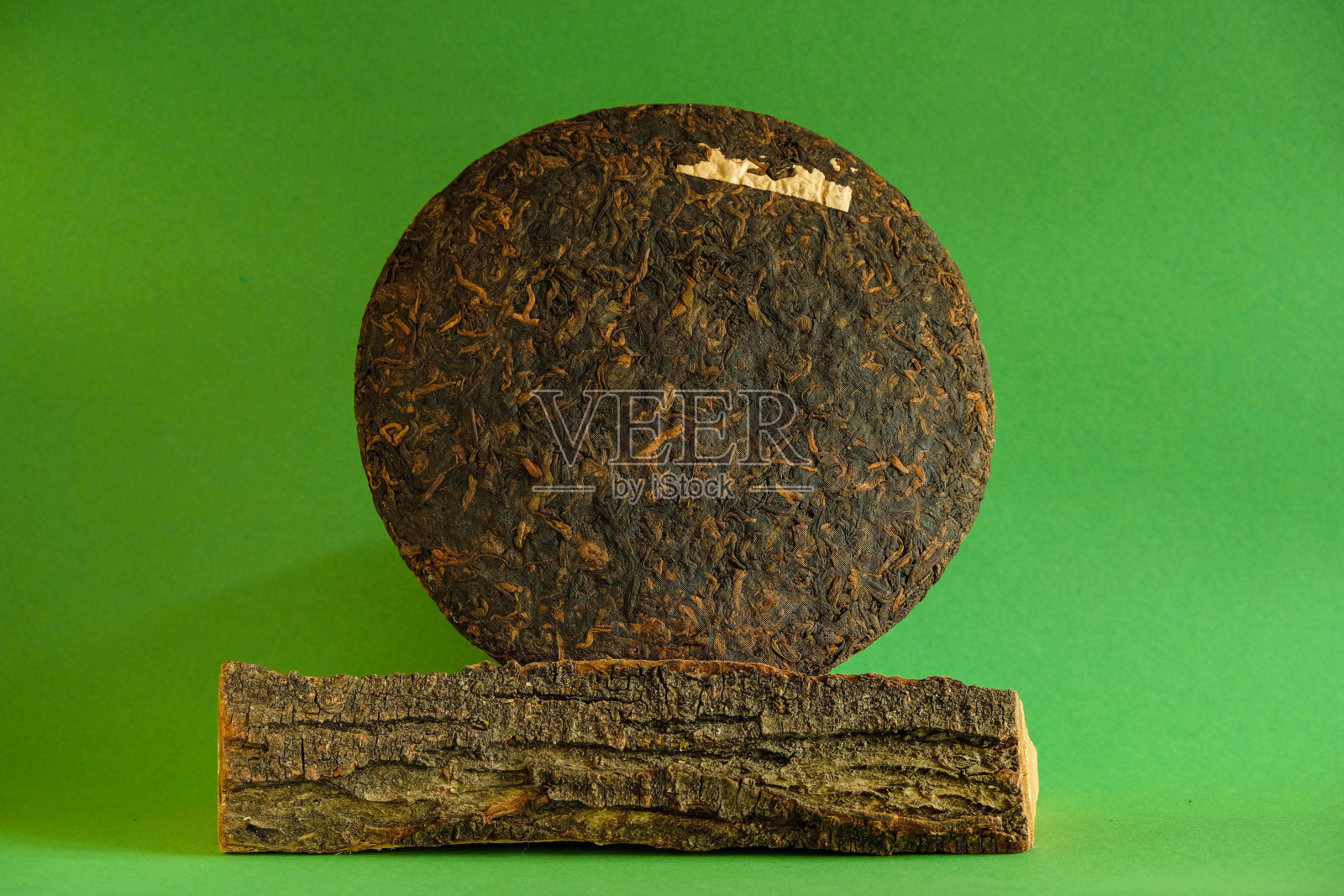 中国云南普洱茶饼。树皮。绿色背景。照片摄影图片