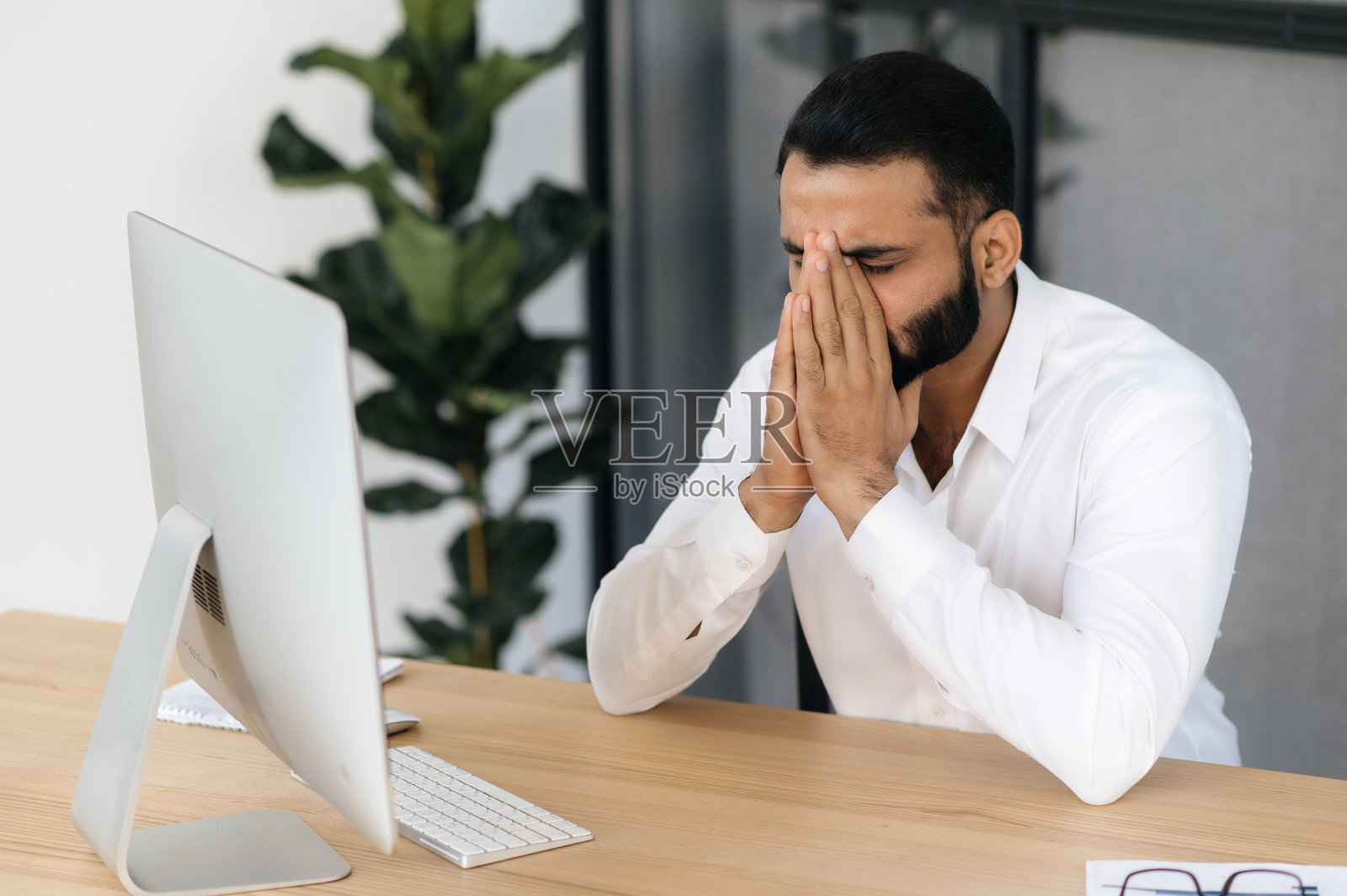 头痛和偏头痛：疲惫的印度或阿拉伯男人，经纪人，金融导师，办公室职员，厌倦工作，压力大，需要休息，用手捂住眼睛照片摄影图片